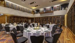 A large library room with round tables and dinner set up