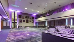 A large room with grey carpet and purple uplighters