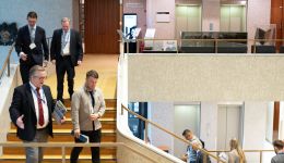 A flights of stairs with a yellow carpet and four man walking down while talking