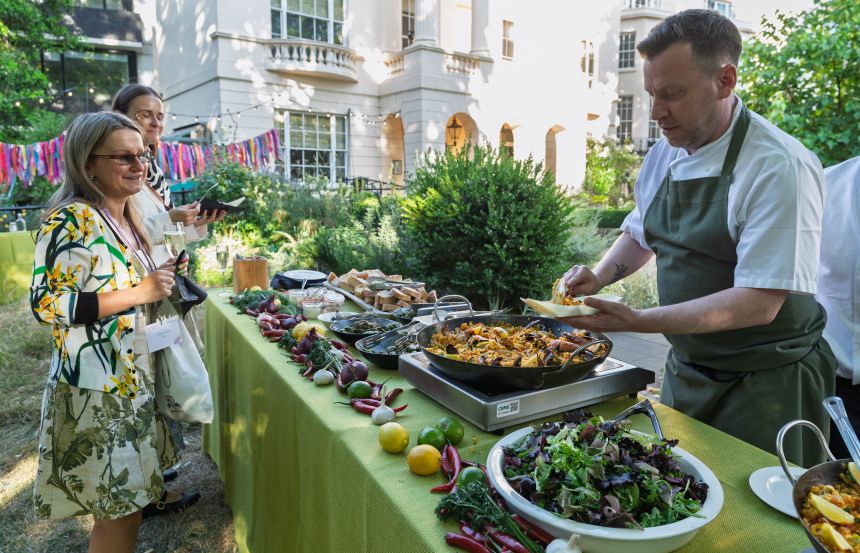 A chef serving paella in a garden