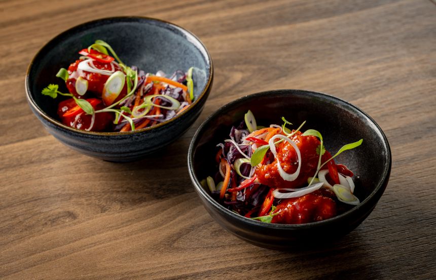 Two black bowls with colourful food inside