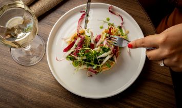 A plate of food shot from the top with a glass of white wine on the side